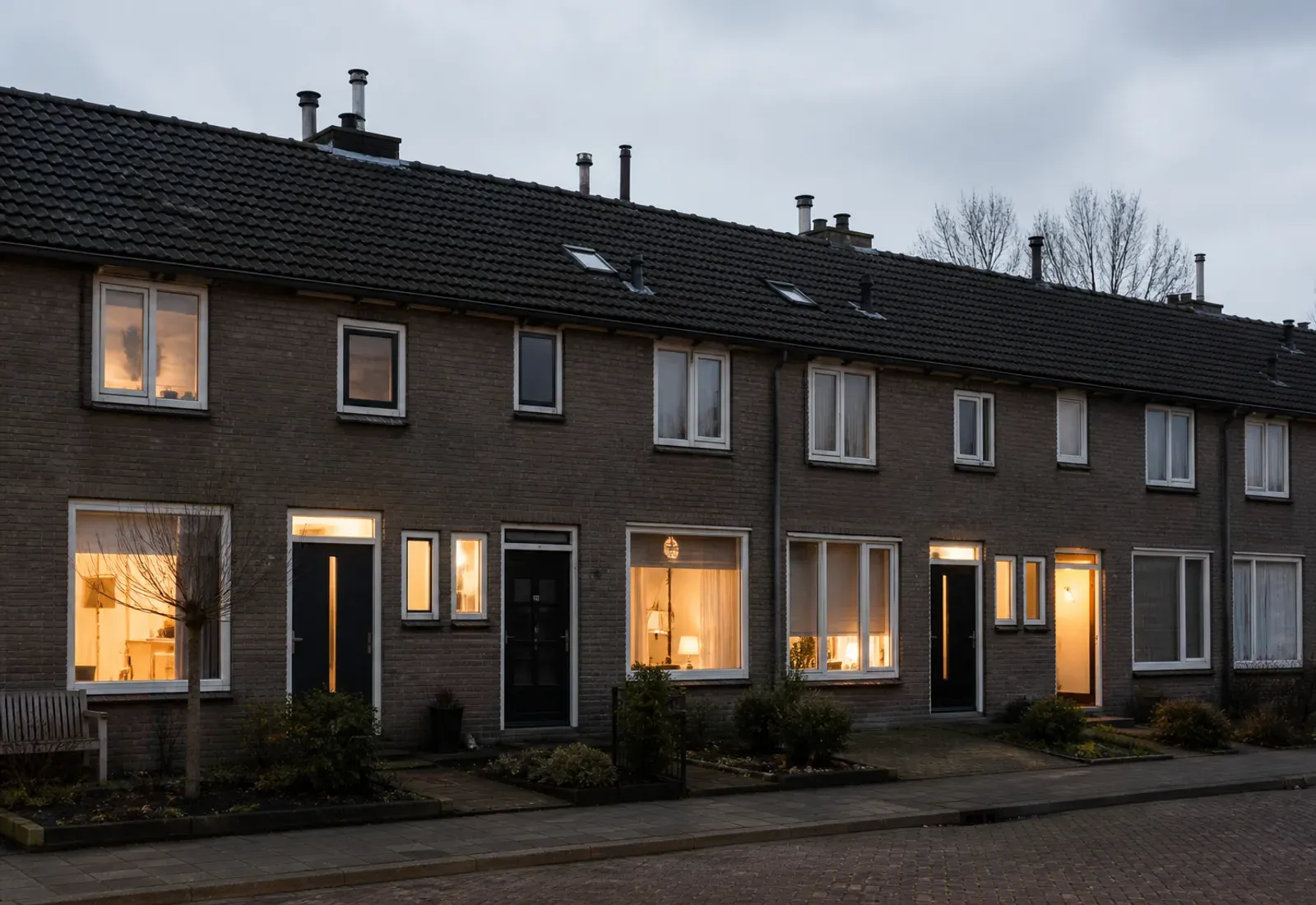 Nederlandse rijtjeshuizen in de vroege avond met verlichte ramen